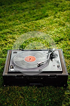 Turntable with LP vinyl record on grass background