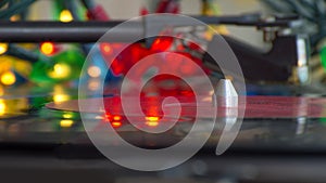 A turntable playing music vinyl record. Colorful lights blurred.