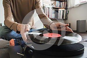 Turntable playing vinyl LP record. Man listening music, relaxing, enjoying life at home.