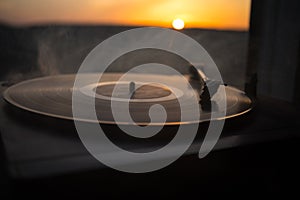 Turntable vinyl record player on the background of a sunset over the mountains. Sound technology for DJ to mix & play music. Black