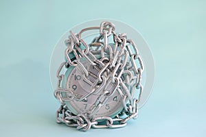 Turquoise alarm clock is wrapped in chrome chain closeup