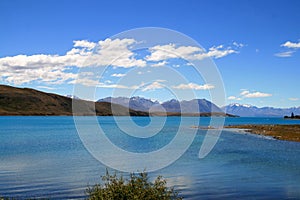 Turquoise blue lake Tekapo surrounded by hills of Southern Alps in back photo