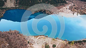 Turquoise blue mirror water with trees in the lake