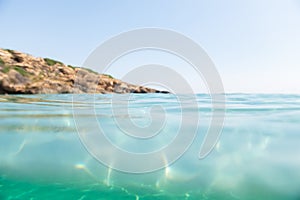 Turquoise blue sea above water surface and underwater. Sun glare at the bottom of ocean. Waves underwater and rays of sunlight