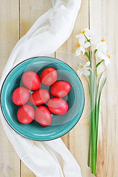 Turquoise bowl with red eggs and daffodil flowers