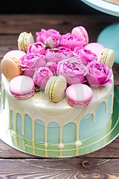 Turquoise cake with white melted chocolate, fresh roses and french macaroons decoration