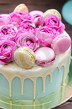 Turquoise cake with white melted chocolate, fresh roses and french macaroons decoration