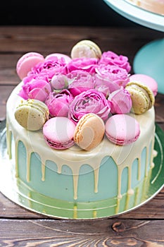 Turquoise cake with white melted chocolate, fresh roses and french macaroons decoration