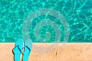 Turquoise flip flops at the edge of pool