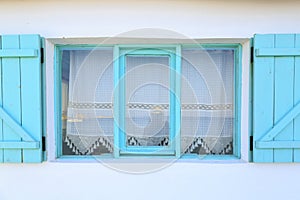 Turquoise framed windows on white wall with curtains in Datca, T