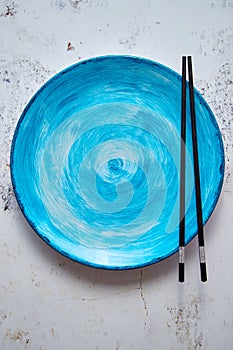 Turquoise hand painted ceramic serving plate with wooden chopsticks on side