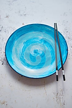 Turquoise hand painted ceramic serving plate with wooden chopsticks on side