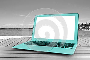 Turquoise Laptop computer on wooden table. Front ocean view. Tropical island background. Open blank laptop computer empty space.