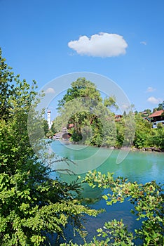 Turquoise Mangfall river and green shrubs, Gmund village upper bavaria. blue sky with cloud