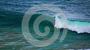 Turquoise ocean wave swelling in slow motion. Foamy powerful barrel rolling