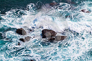 Turquoise ocean waves crashing on coastal rocks