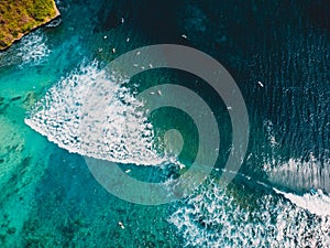 Turquoise ocean with waves and surfers, aerial shot