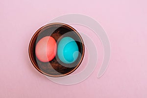 Turquoise and pink Easter eggs on a wooden plate on a pink background. Easter concept.