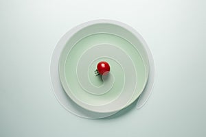 Turquoise plate with red tomato on a light background