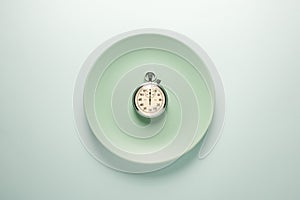 Turquoise plate with a stopwatch on a light background top view. Fast food concept