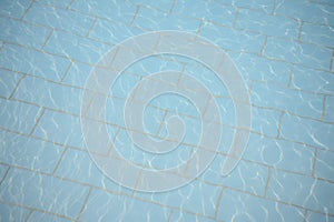 Turquoise pool water with small ripples and sun reflections on the surface.