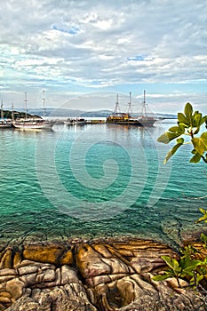 Turquoise sea, harbor with old traditional sailing ships in Sithonia, Halkidiki Peninsula, Greece,