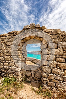 Turquoise sea viewed through window of derelict building in Corsica