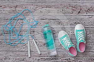Turquoise sneakers and a high-speed jump rope on a floor. Sports style. Flat lay.