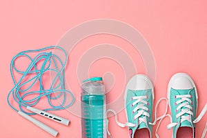 Turquoise sneakers and a high-speed jump rope on a pink background. Sports style. Flat lay.