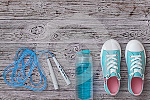 Turquoise sneakers and a high-speed jump rope on a wooden floor. Sports style. Flat lay.