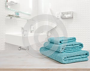 Turquoise spa towels pile on wood over blurred bathroom background