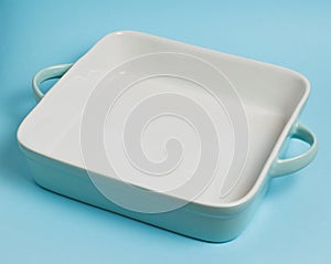Turquoise square ceramic baking dish on a blue background