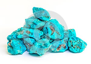 Turquoise stones heap on white. Good quality, very good colored rough turquoise stones. Using for its peaceful energy and for its