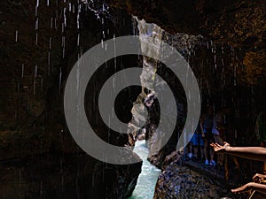 People's hands reach for dripping drops of icy water flowing down from the rocks.