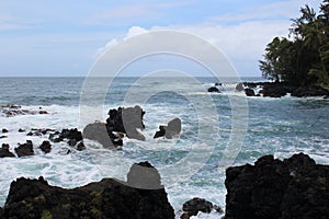 Turquoise water rushing into a black lava rocky cove at Wailua Lookout in Haiku, Maui, Hawaii