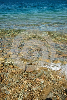 Turquoise water on stoney beach.