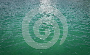 Turquoise water surface aerial view,  green sea surface in windy day forming many little waves reflecting the sun