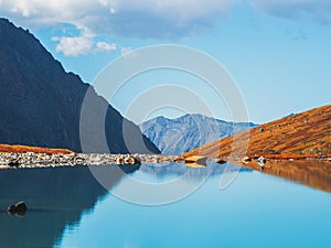 Turquoise water surface of the mountain lake is like a mirror. Picturesque mountain lake in the summer day, Altai. Beautiful