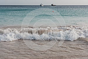 Turquoise water, white sand and waves in Carlisle Bay, Bridgetown, Barbados, at dusk.