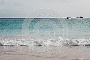 Turquoise water, white sand and waves in Carlisle Bay, Bridgetown, Barbados, at dusk.