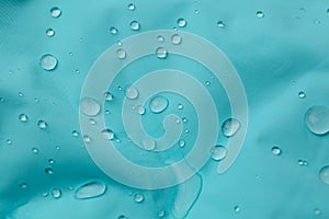 Turquoise waterproof fabric with water drops as background, closeup