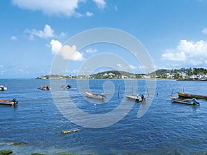 Turquoise waters of the Caribbean Sea with traditional fishing boats and the silhouette of a small town in the background. Idyllic