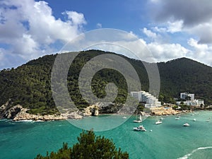 Turquoise waters and pine covered hills of Cala Llonga bay, Med