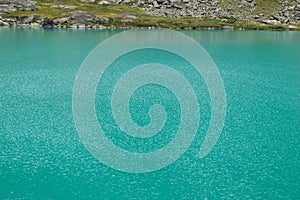 Turquose water texture and bank of the Akchan lake in the Altai mountains, Russia