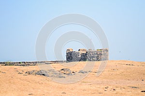 Turret of An Lohagad Fort At The Edge Of A Cliff with a mountainscape in the background