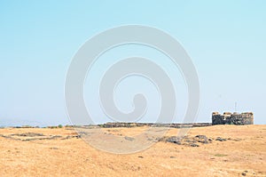 Turret of An Lohagad Fort At The Edge Of A Cliff with a mountainscape in the background