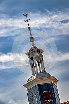 Turret with rooster against blue sky with clouds.