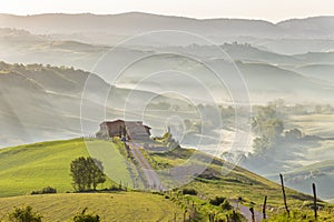 Tuscan farm landscape with morning fog in the rolling landscape