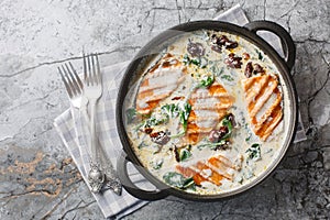 Tuscan salmon dish of grilled salmon fillet with cream sauce, garlic, sun-dried tomatoes and spinach closeup in the pan.