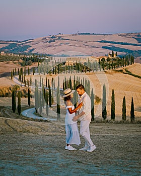 Tuscany, Crete Senesi rural sunset landscape. Countryside farm, cypresses trees, green field, sun light and cloud. Italy